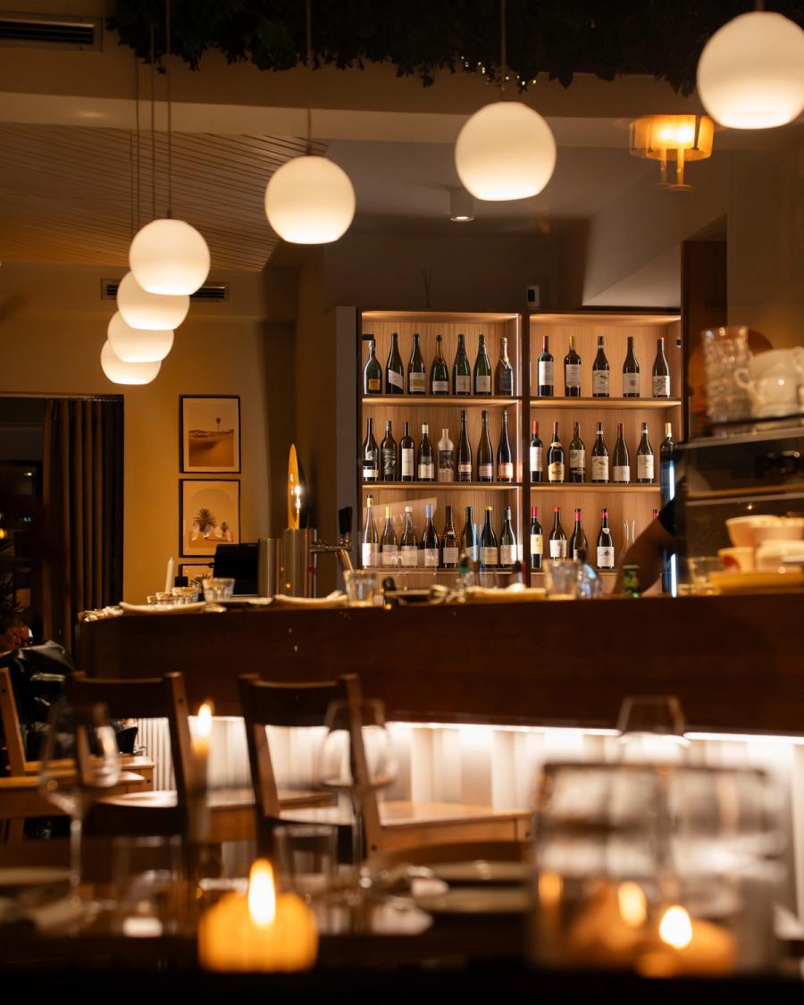Abendstimmung im Nomad Berlin-Mitte: Bar mit Weinwand, Pendelleuchten und Kerzen