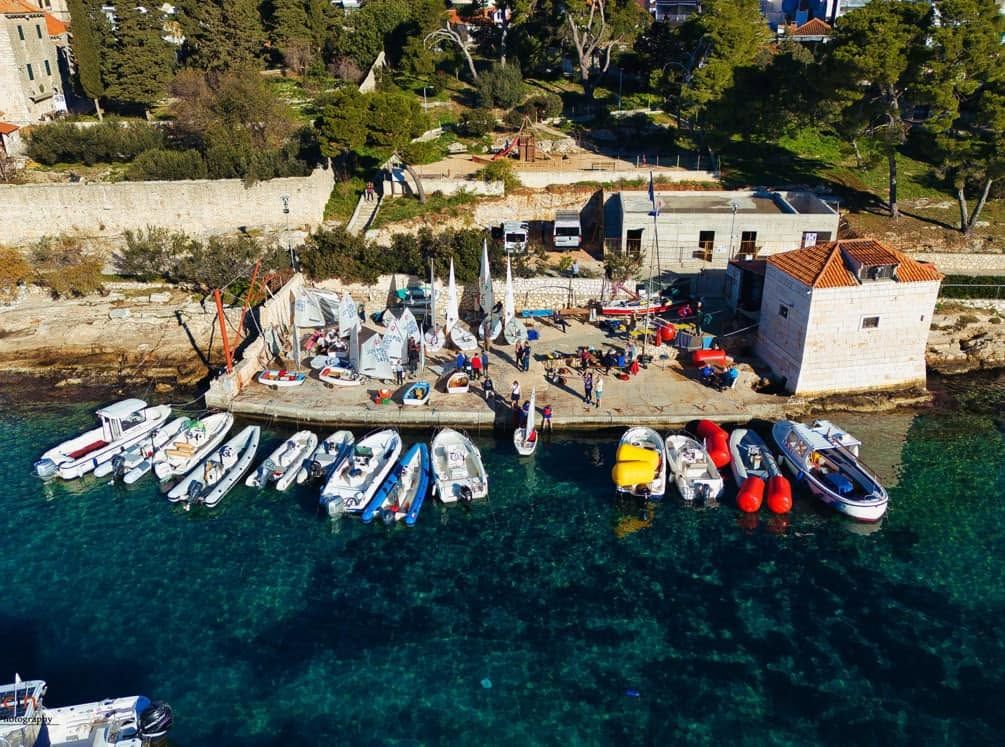 Stari Macel i klupska riva u Križnoj luci iz zraka — optimisti, gumenjaci i jedriličari na rivi