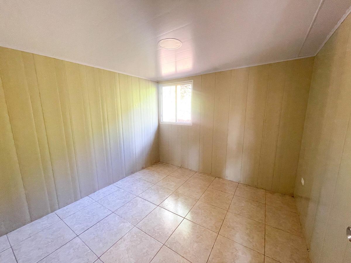 Un cuarto vacío de la casa modelo, con piso de azulejo y una ventana.