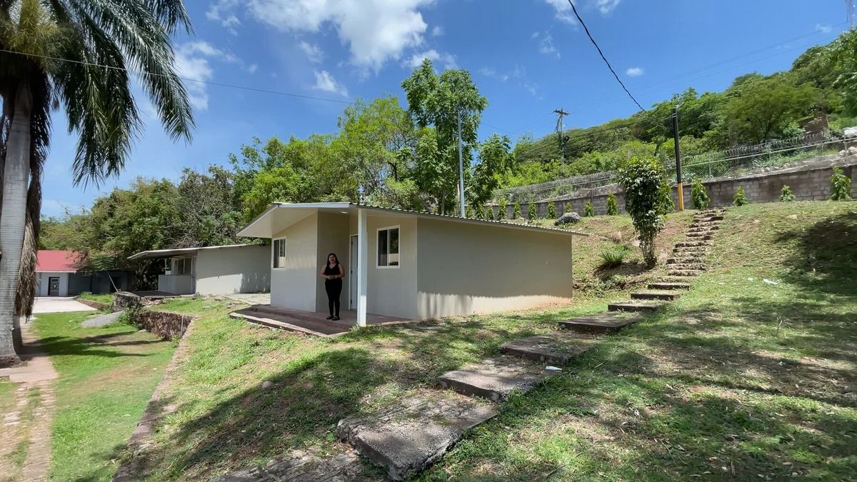 La casa modelo, con gradas de concreto subiendo por el cerro y una palmera a un lado.