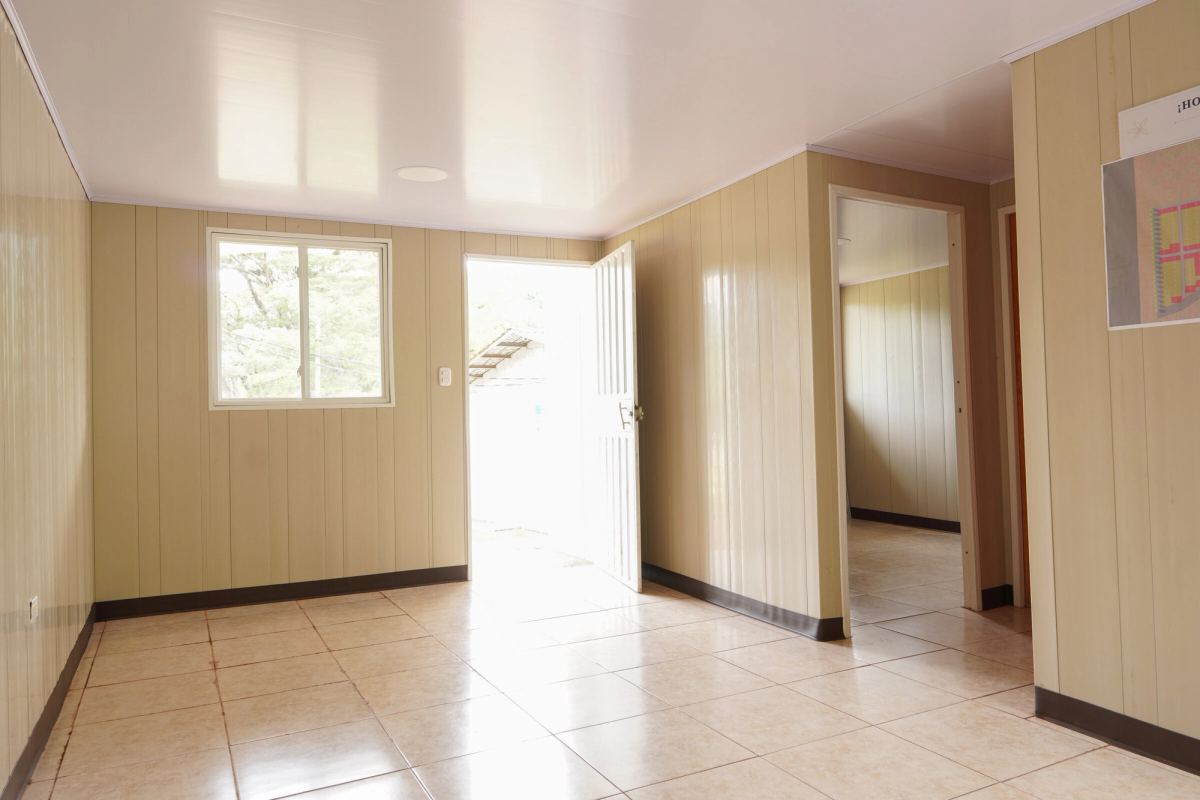 La sala de la casa modelo, con la puerta abierta a la calle y el pasillo hacia los cuartos.