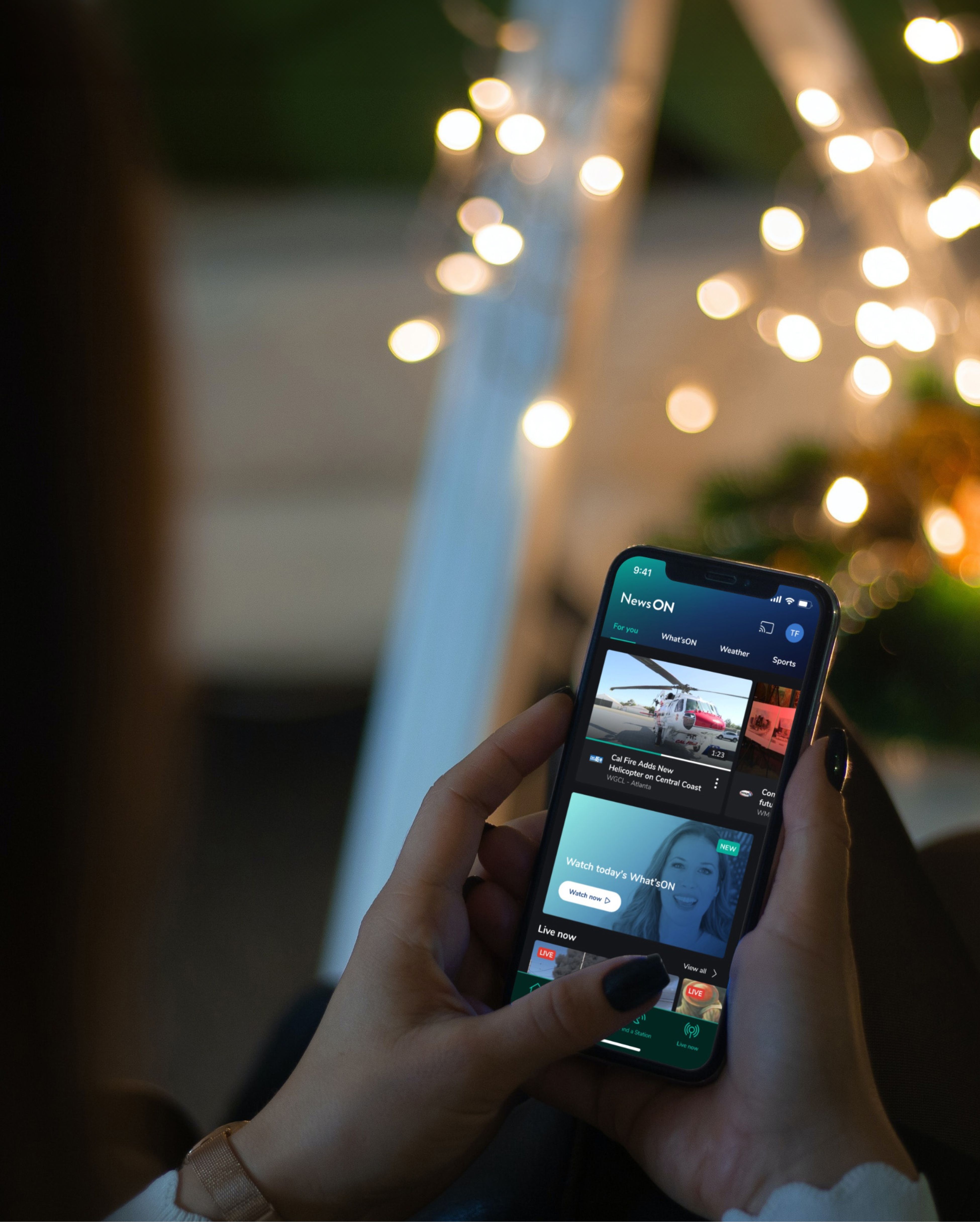 Back view of a woman holding a mobile device. The screen displays the mobile app home screen of NewsON consisting of news items.