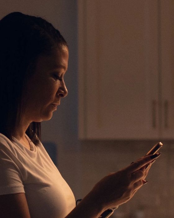 Side view of a woman holding her phone and looking at the screen.