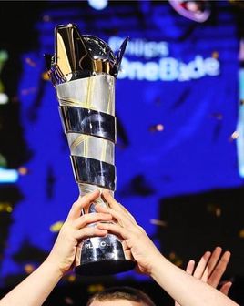 Two hands lifting up the FIFAe World Cup trophy.