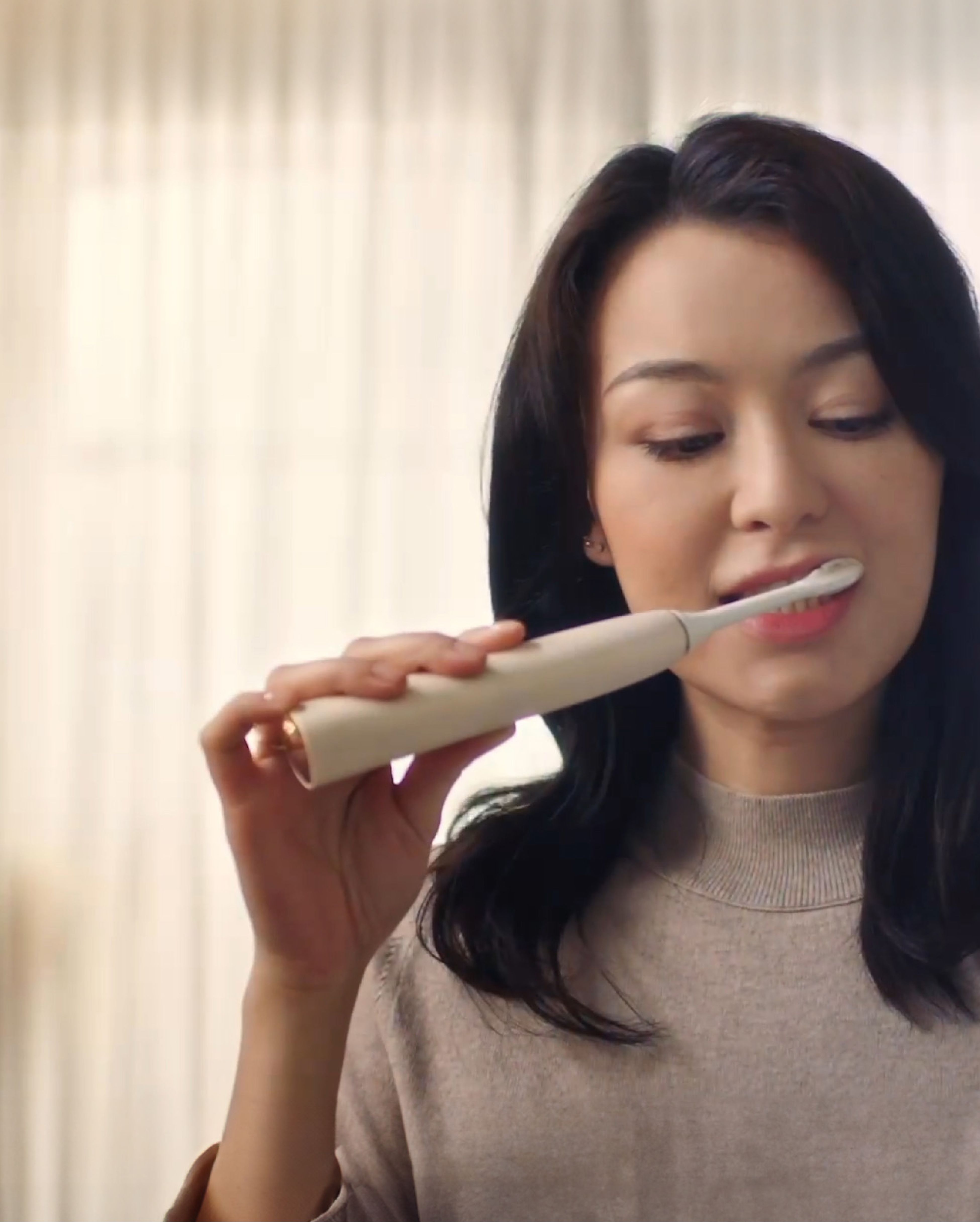 Woman brushing her teeth with a Philips electric toothbrush.