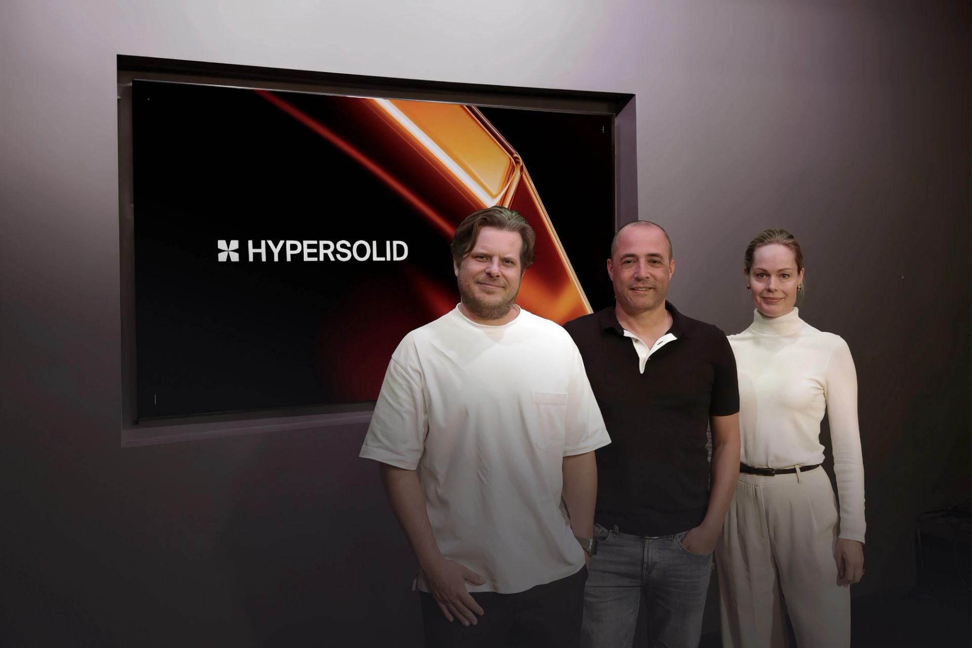 Hypersolid's US-CEO Nik Nieuwenhuijs (left), group-CEO Schalk Stalman (middle), and group CCO Rianne Meijerman (right) standing in front of a screen displaying Hypersolid's logo.