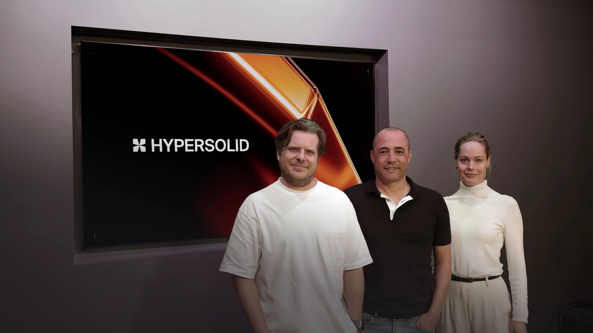 Hypersolid's US-CEO Nik Nieuwenhuijs (left), group-CEO Schalk Stalman (middle), and group CCO Rianne Meijerman (right) standing in front of a screen displaying Hypersolid's logo.