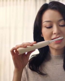 Woman brushing her teeth with a Philips electric toothbrush.