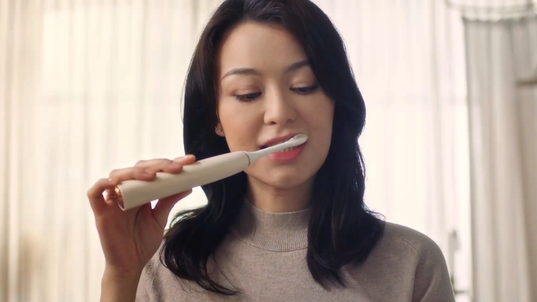 Woman brushing her teeth with a Philips electric toothbrush.