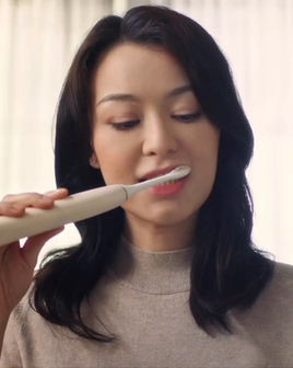 Woman brushing her teeth with a Philips electric toothbrush.