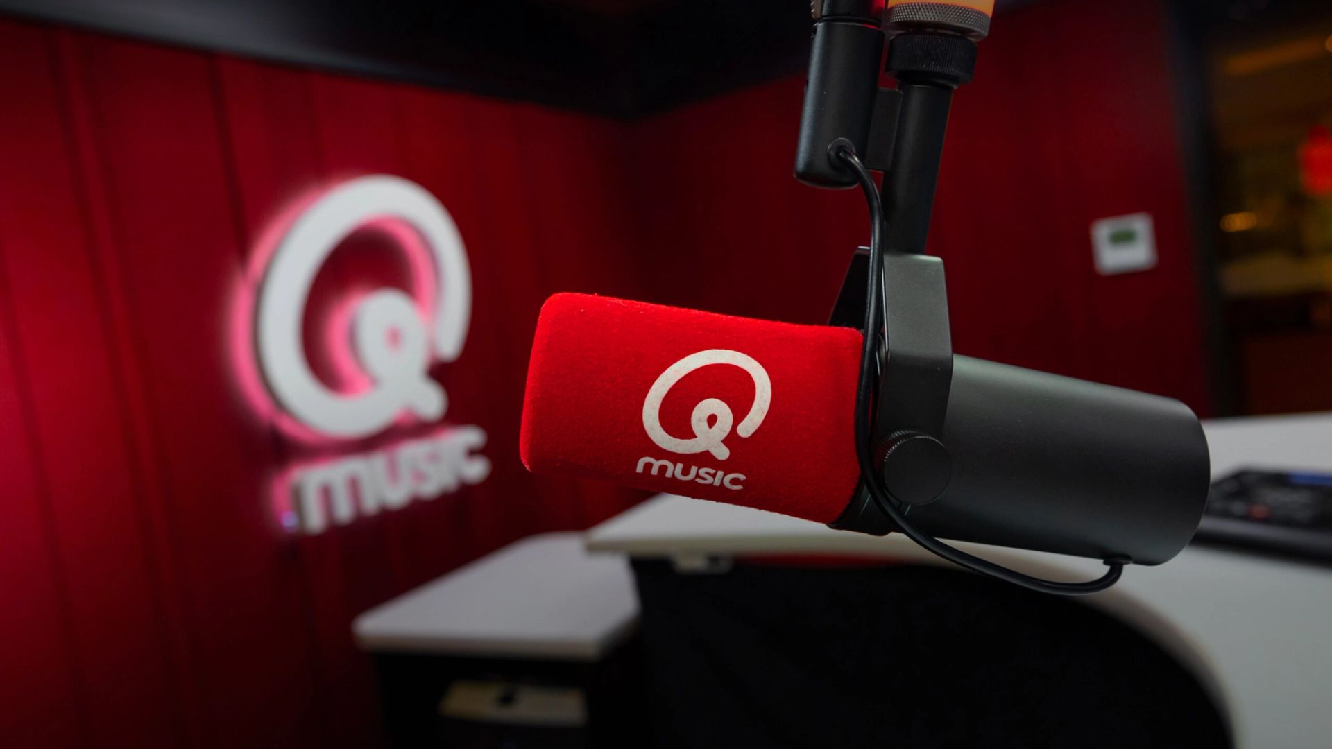 A studio setup with a microphone and the Qmusic logo, used as the case hero image for our Qmusic case.