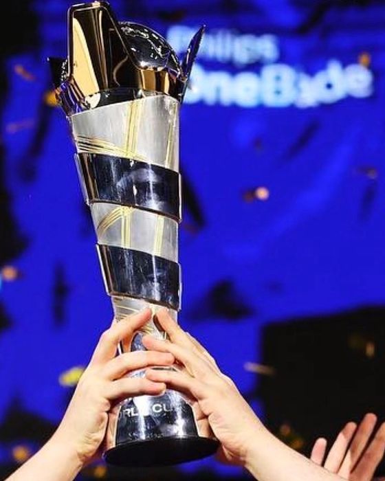 Two hands lifting up the FIFAe World Cup trophy.