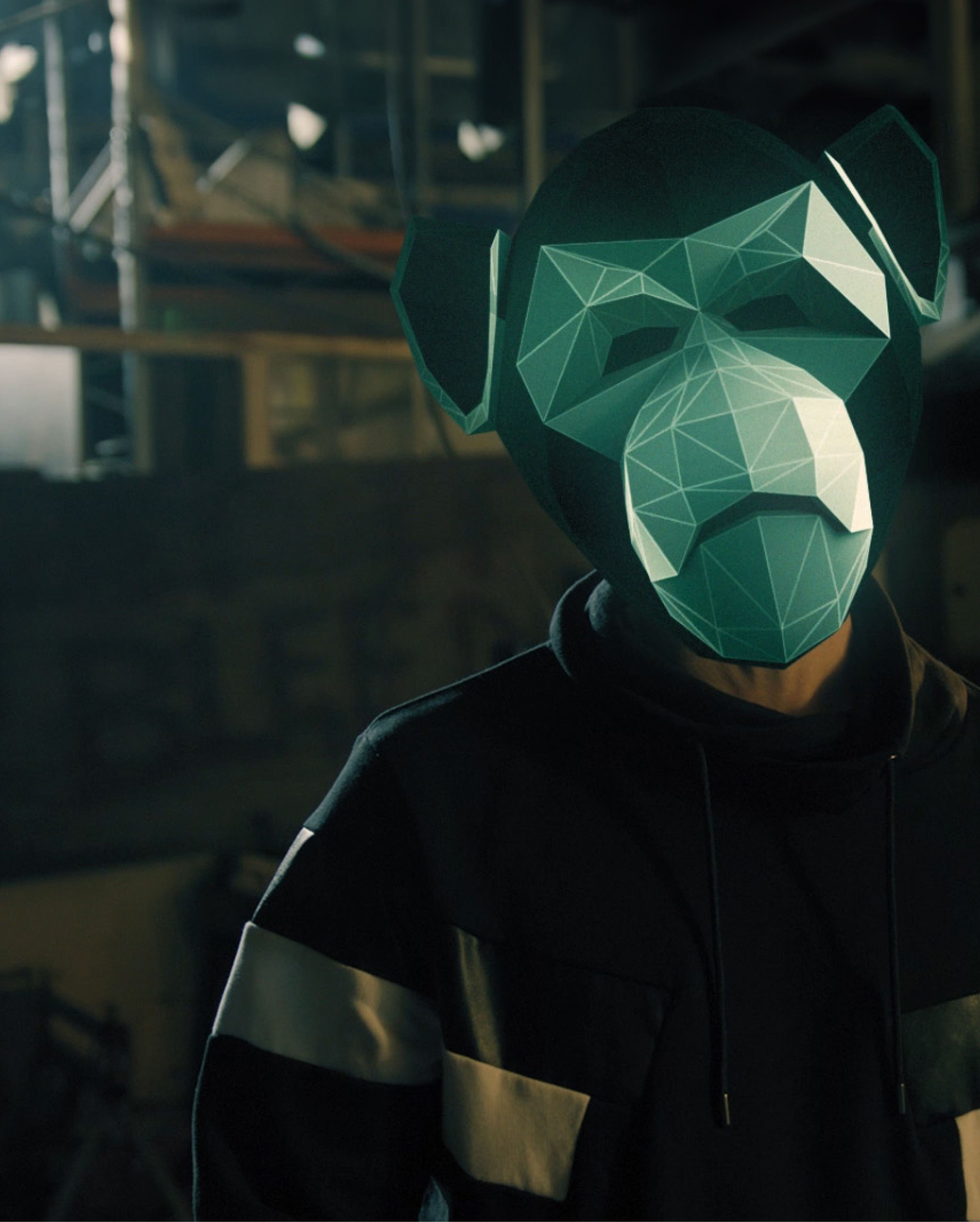 Person wearing a green monkey mask standing inside an industrial workplace.