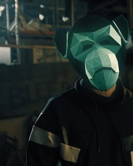 Person wearing a green monkey mask standing inside an industrial workplace.
