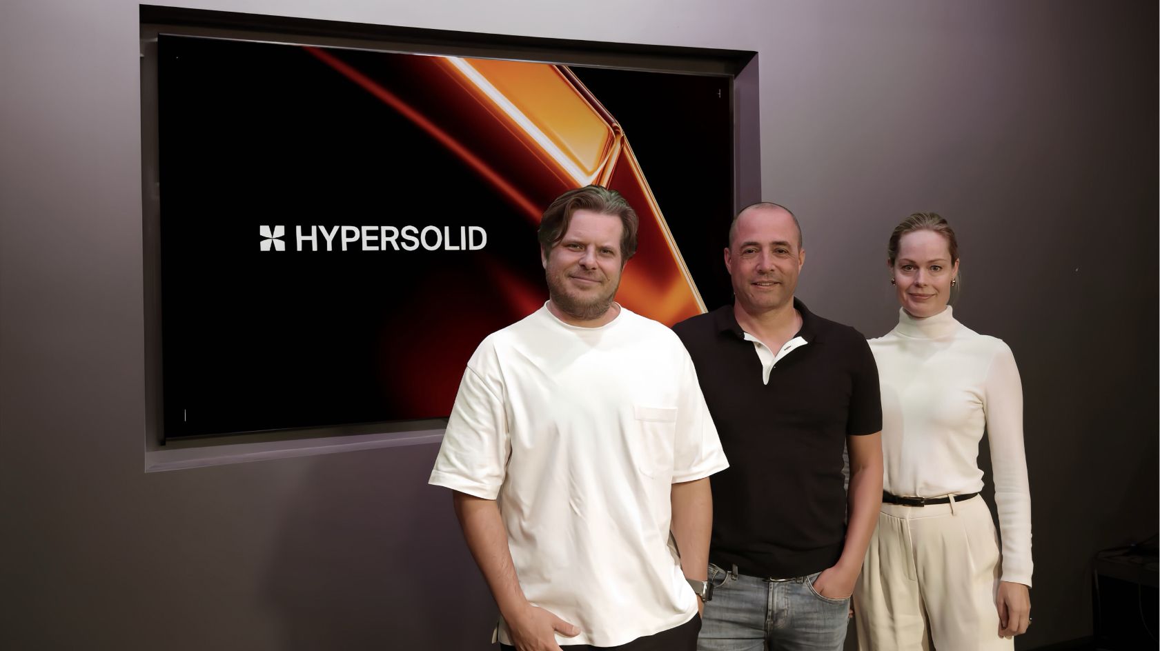 Hypersolid's US-CEO Nik Nieuwenhuijs (left), group-CEO Schalk Stalman (middle), and group CCO Rianne Meijerman (right) standing in front of a screen displaying Hypersolid's logo.