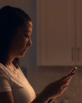 Side view of a woman holding her phone and looking at the screen.