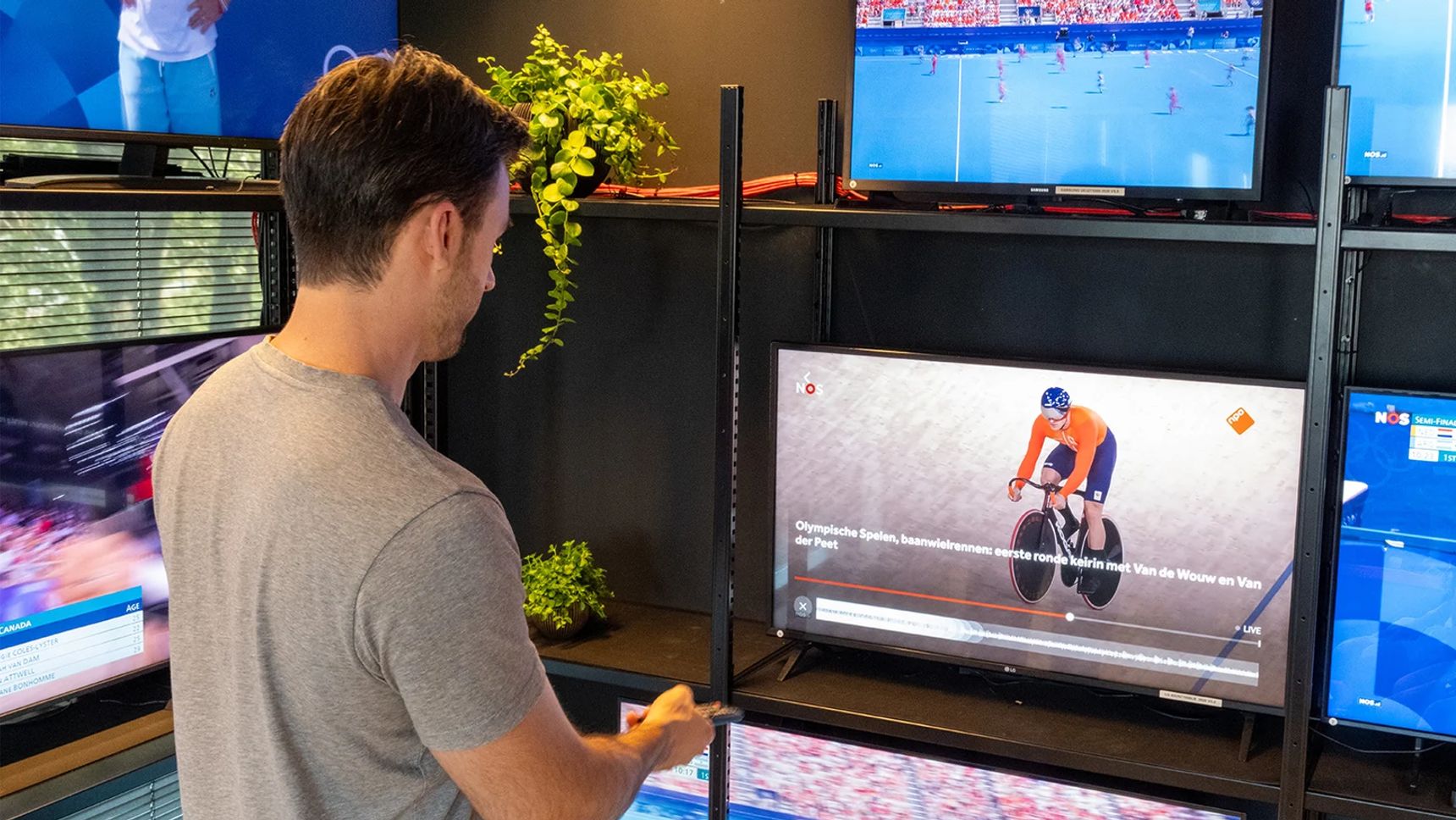 An employee holding a remote control, operating a smart TV in Hypersolid's OTT test lab in Alkmaar.