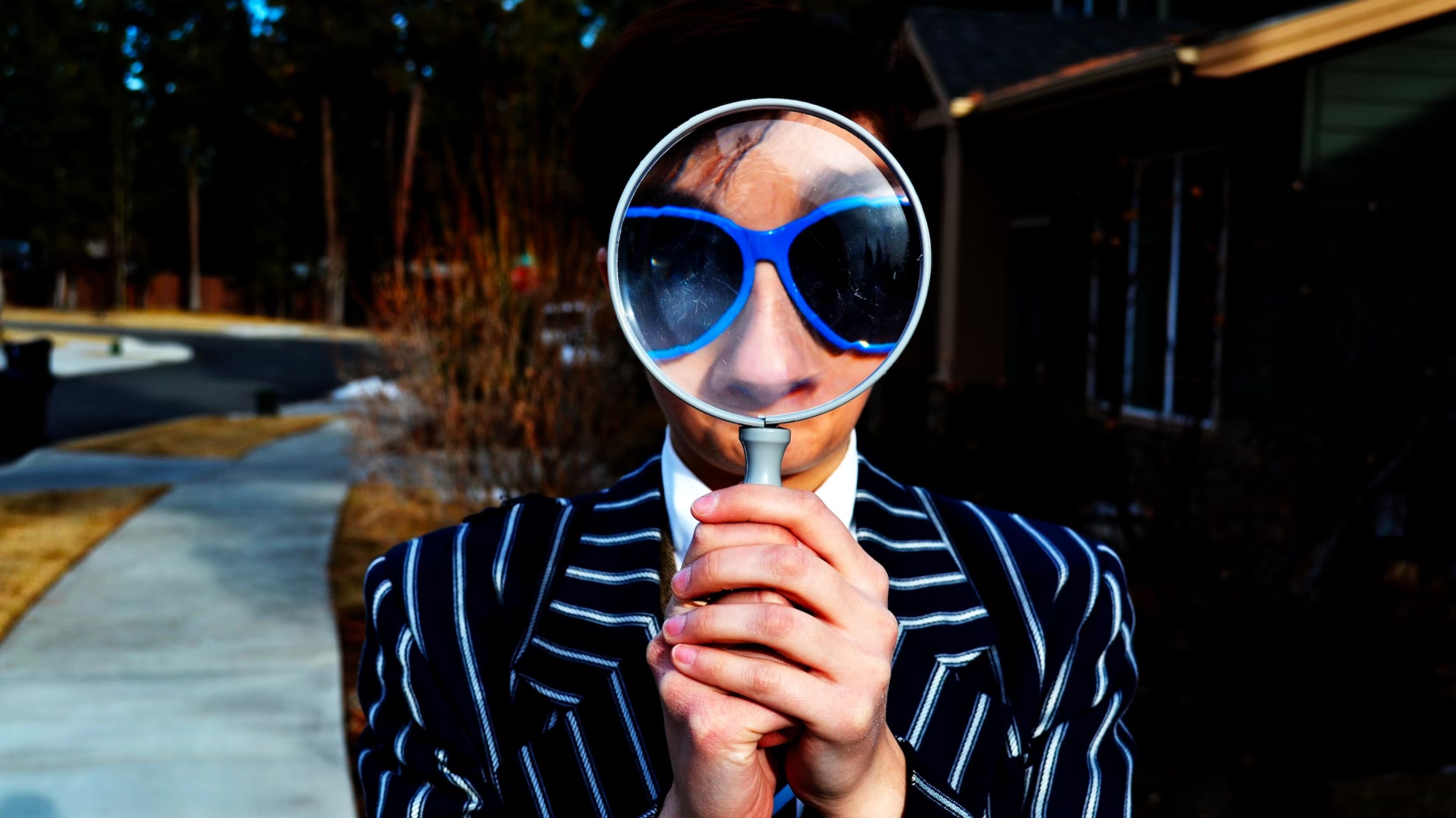 A man's face with glasses seen through a magnifying glass, used as the hero image for the article "It’s Called UX/UI! Look It Up!".