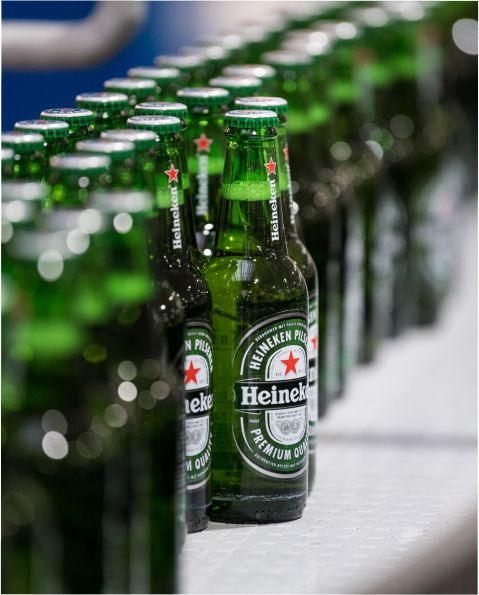 Dozens of Heineken bottles lined up at an assembly line.