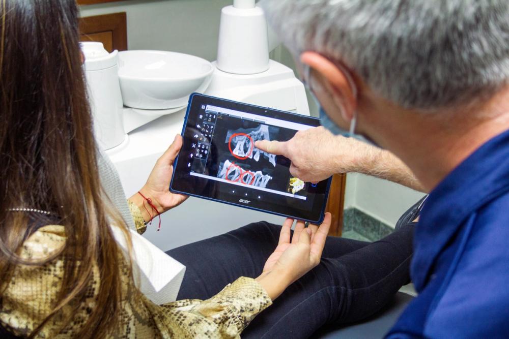 Dental patient looking at x-ray on tablet with dentist