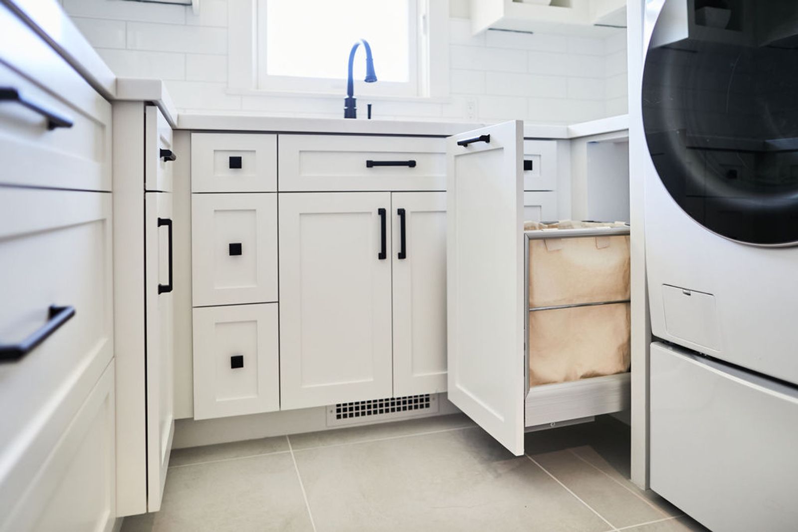 A perfect white shaker laundry room with pull-out hamper