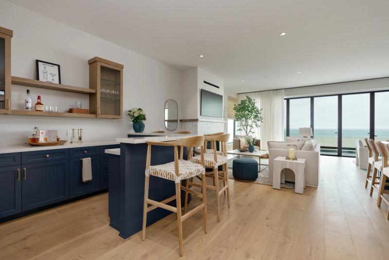 A bright, open-concept room featuring custom bar cabinets in painted blue, and white oak uppers with floating shelves.