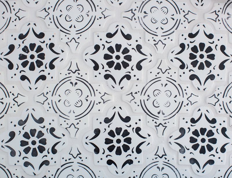 A close-up of a repeating black and white decorative tile or panel pattern featuring floral and geometric motifs in a classic Mediterranean or Talavera style.