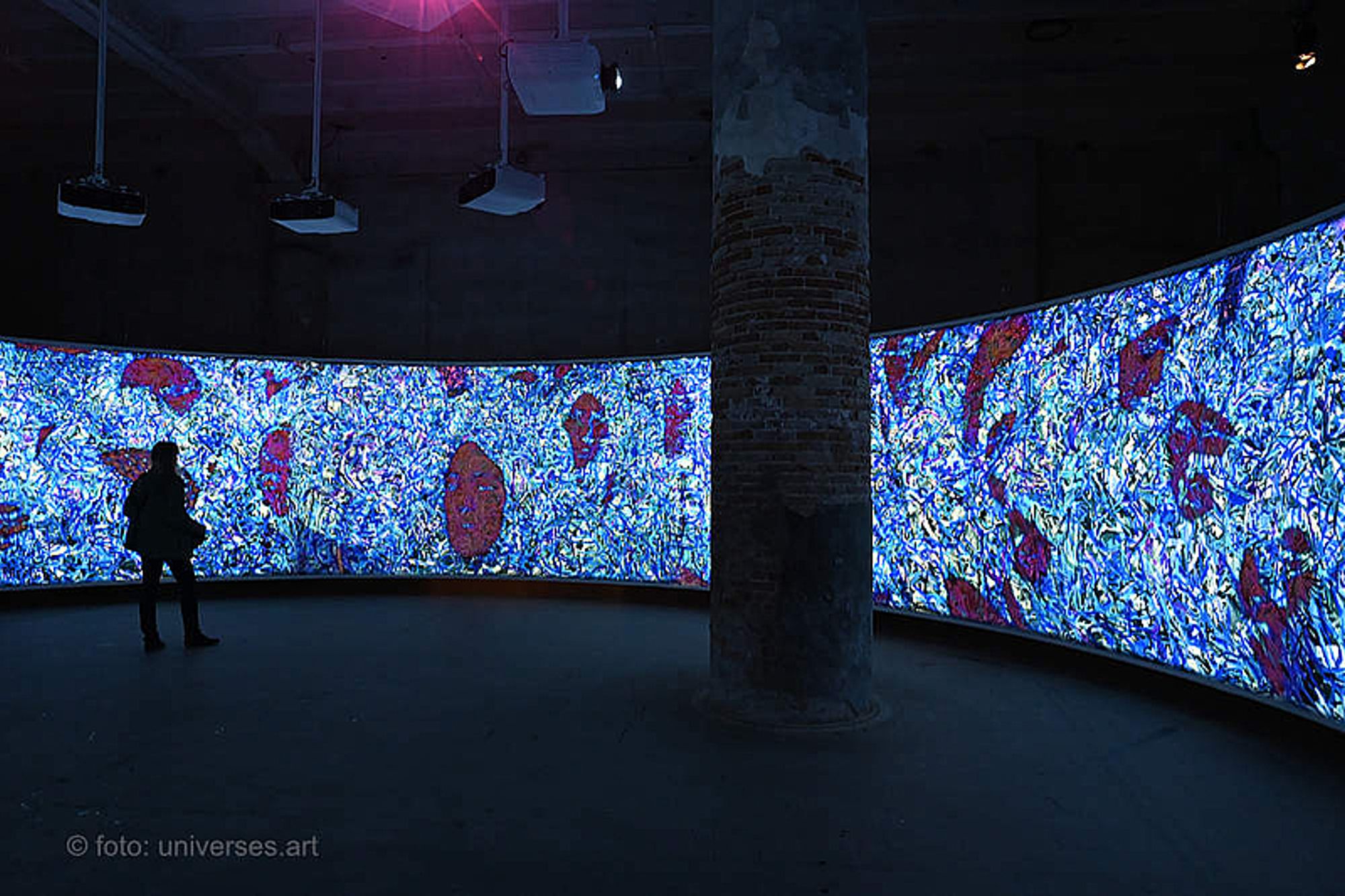 Circular canvas enclosure with projected faces of crowds inside the Arsenale's Corderie.