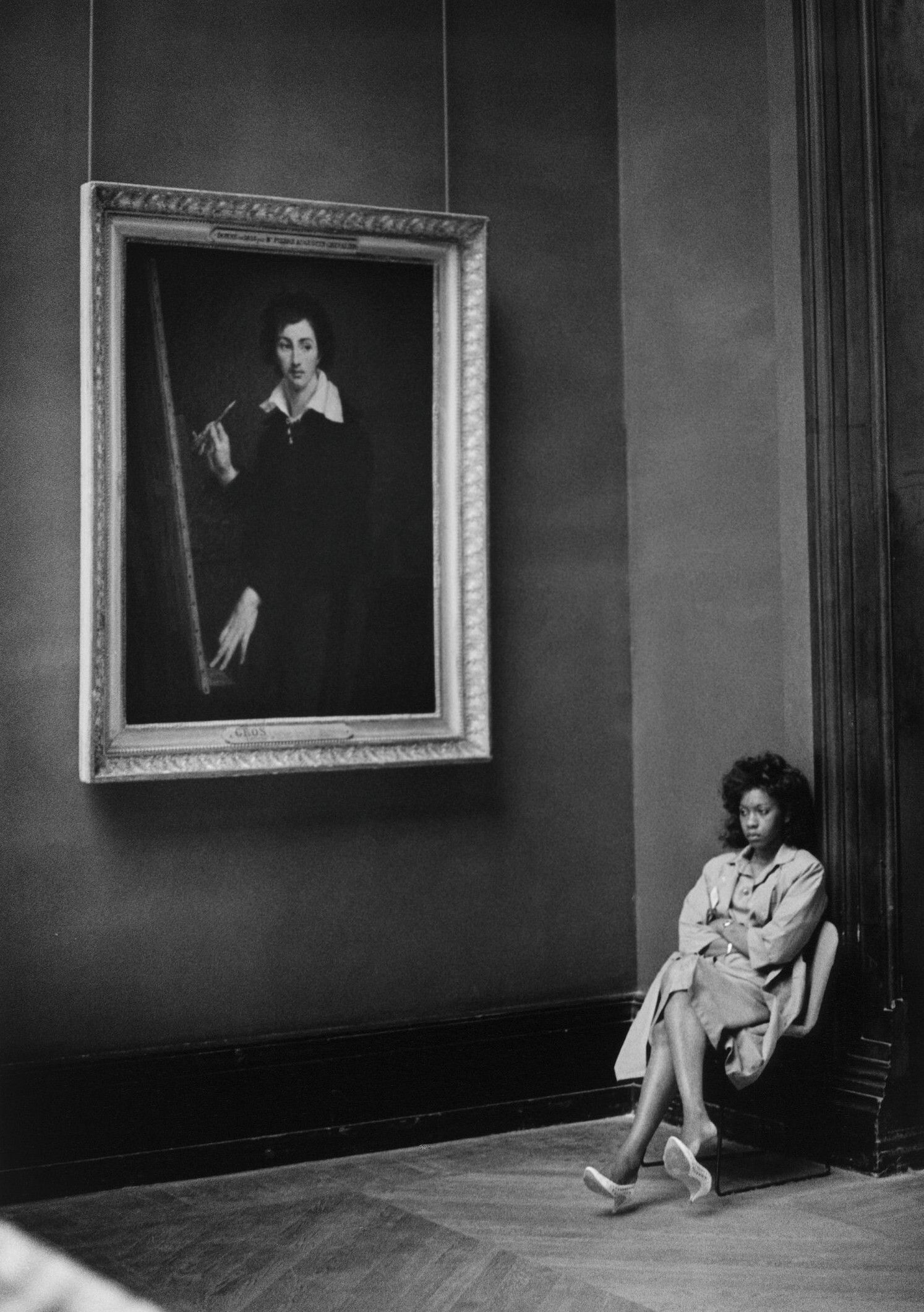 Barbara Klemm's black and white photograph of a woman seated in the Louvre beneath a large portrait.