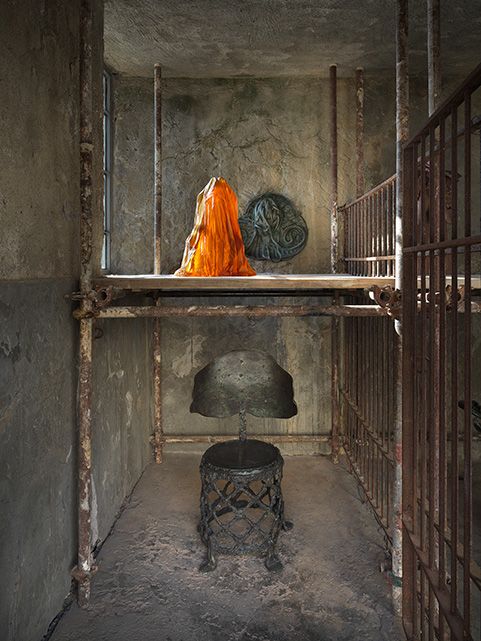 Bronze and glass sculptures by Andra Ursuța installed inside the stone walls of the old slaughterhouse on Hydra, sea visible through the openings.