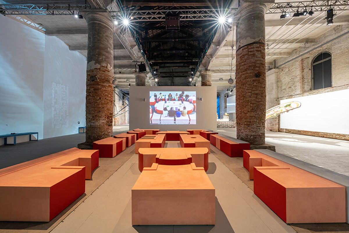 Interior view of DAAR's installation at the Corderie, Arsenale, with terracotta modules arranged as seating in front of a projected film.