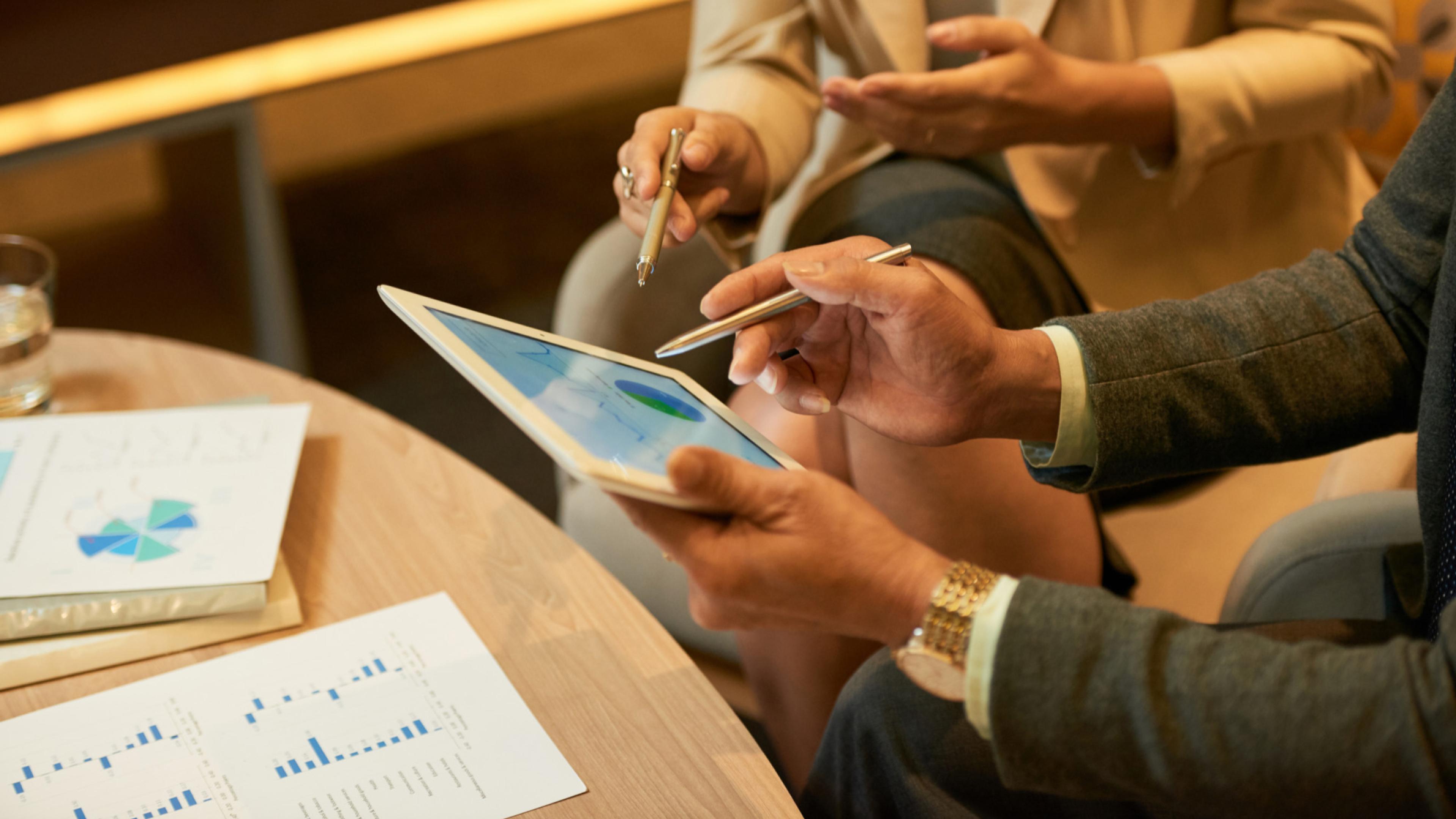 Two business people analyzing data on a tablet display with pens