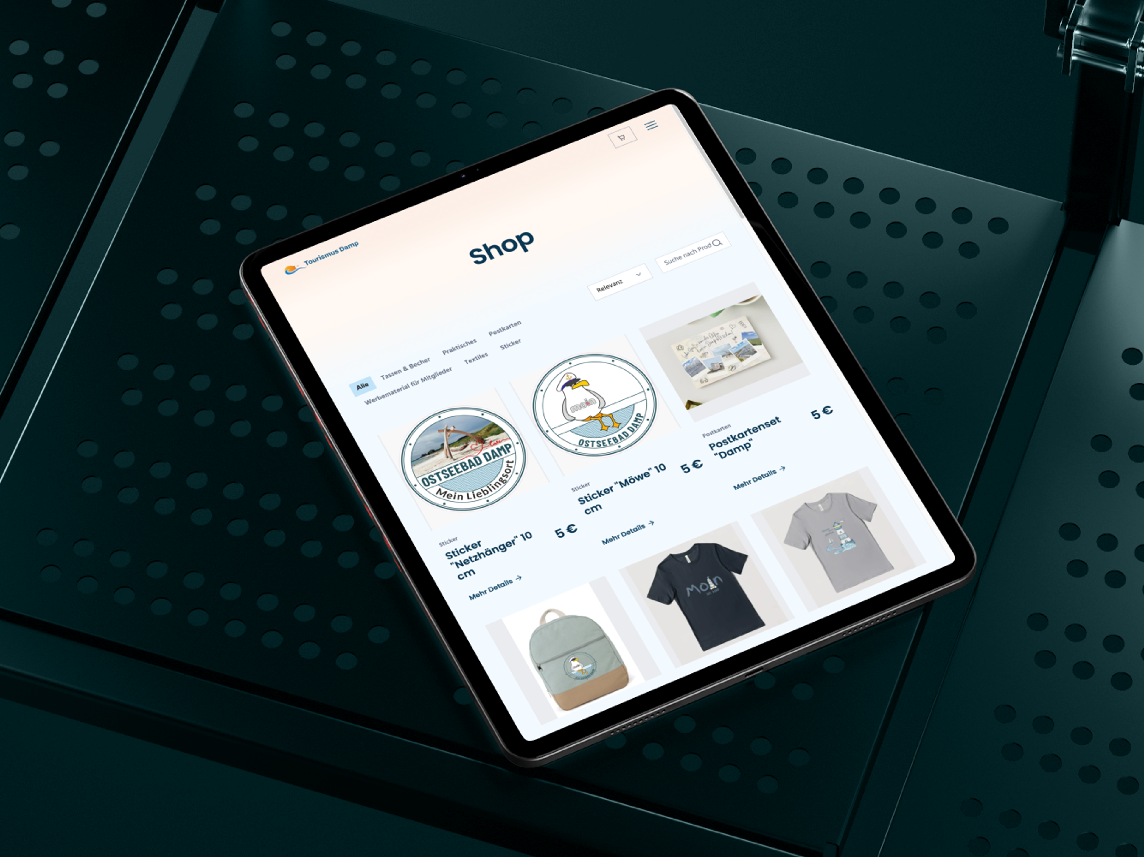 A tablet shows an online store page with various products such as stickers and T-shirts