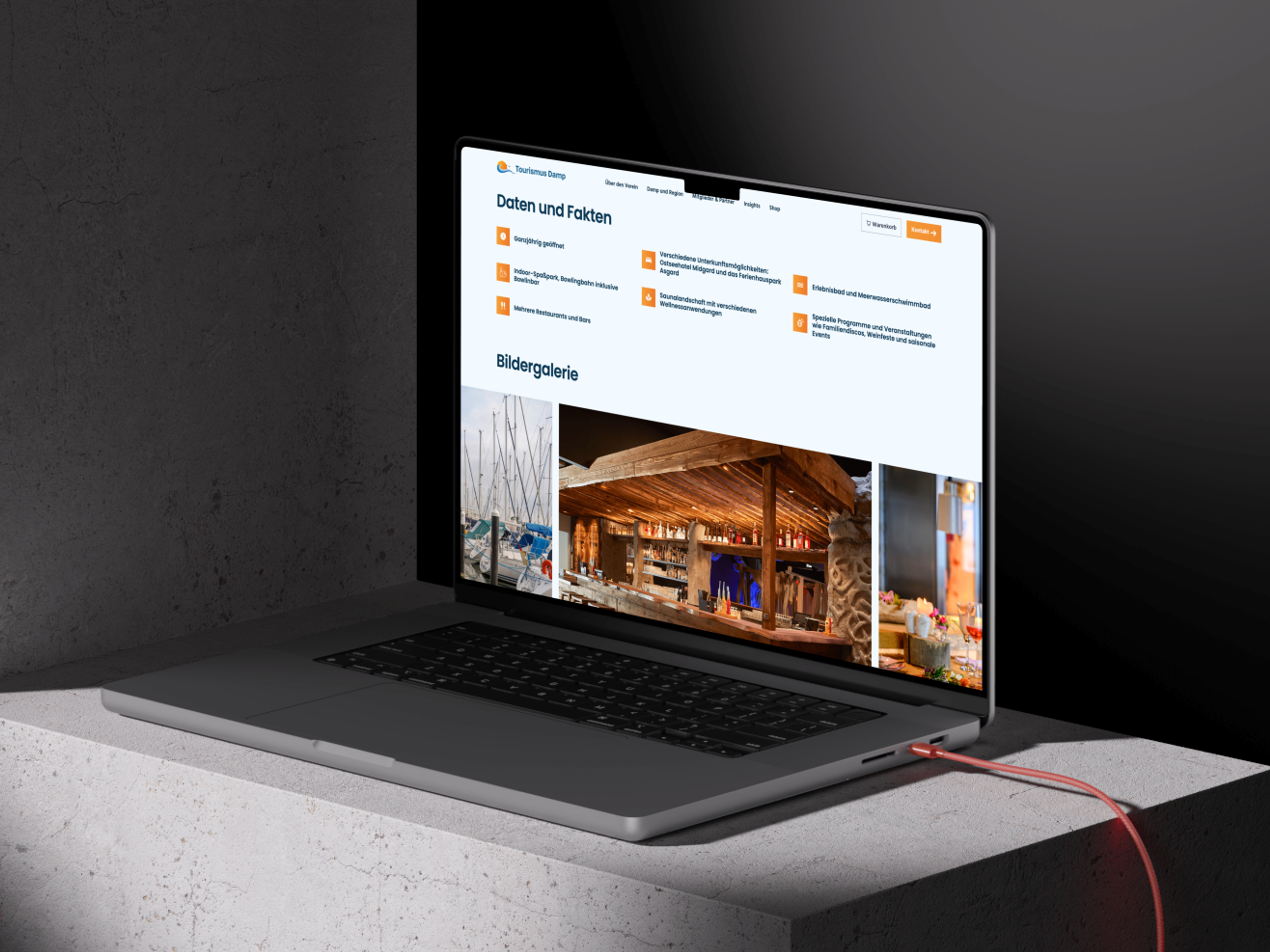 Ein Laptop zeigt eine Tourismus-Website mit Bildern von Yachten und einem rustikalen Restaurant auf einem Betonblock.