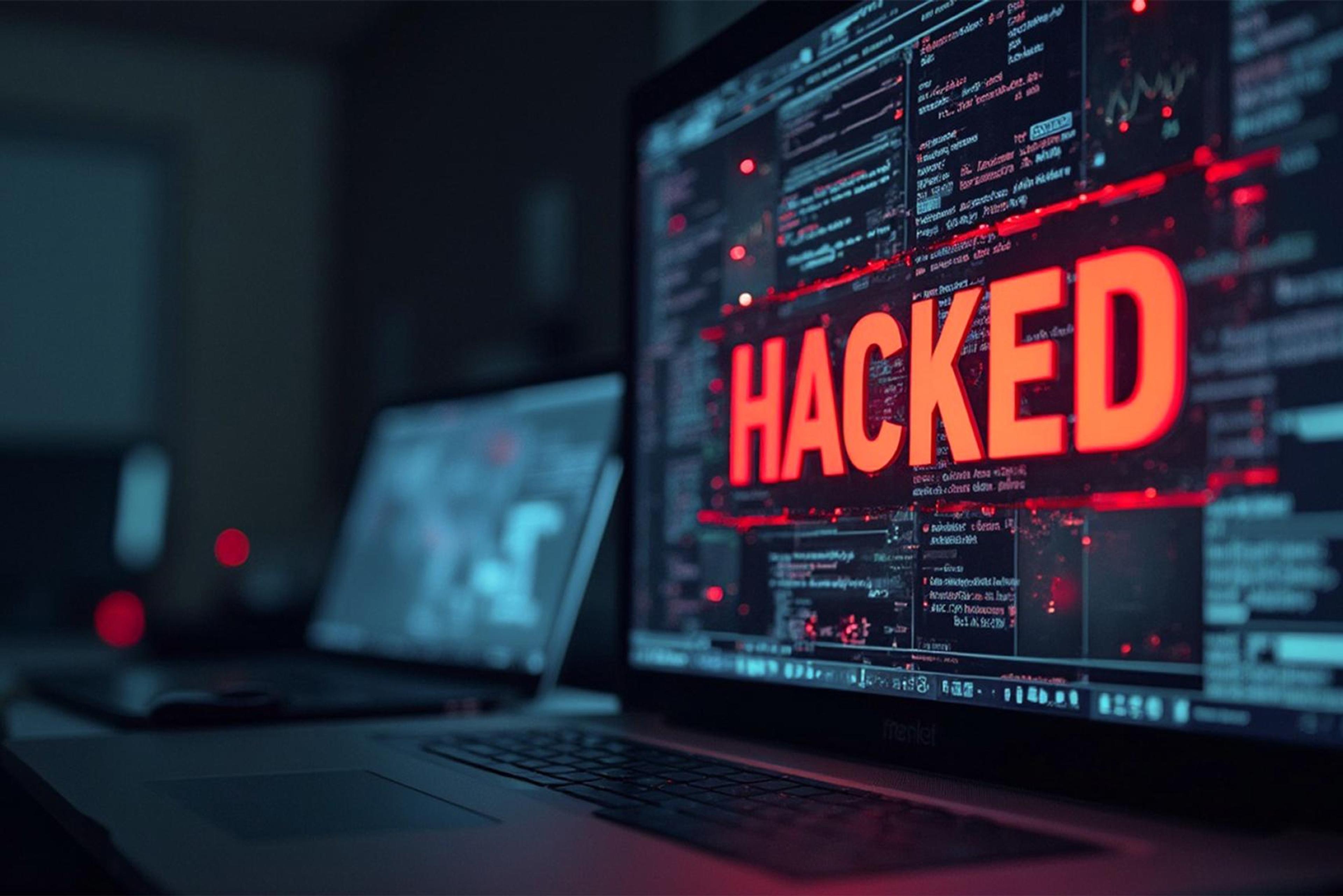 На экране компьютерного монитора отображается красный текст «Hacked» на фоне программного кода