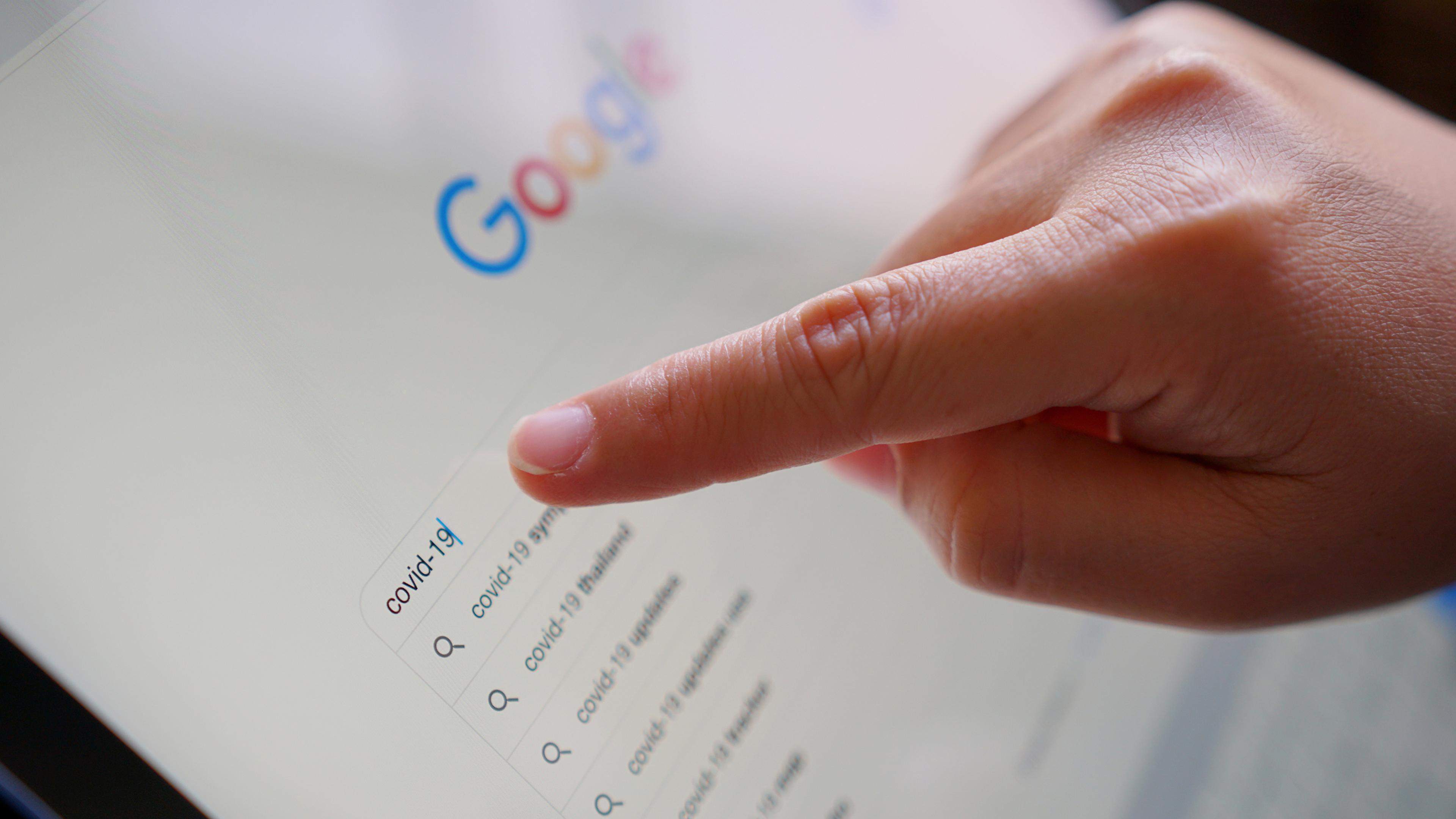 Nærbilde av en finger som peker på Google-søket på en nettbrettskjerm.