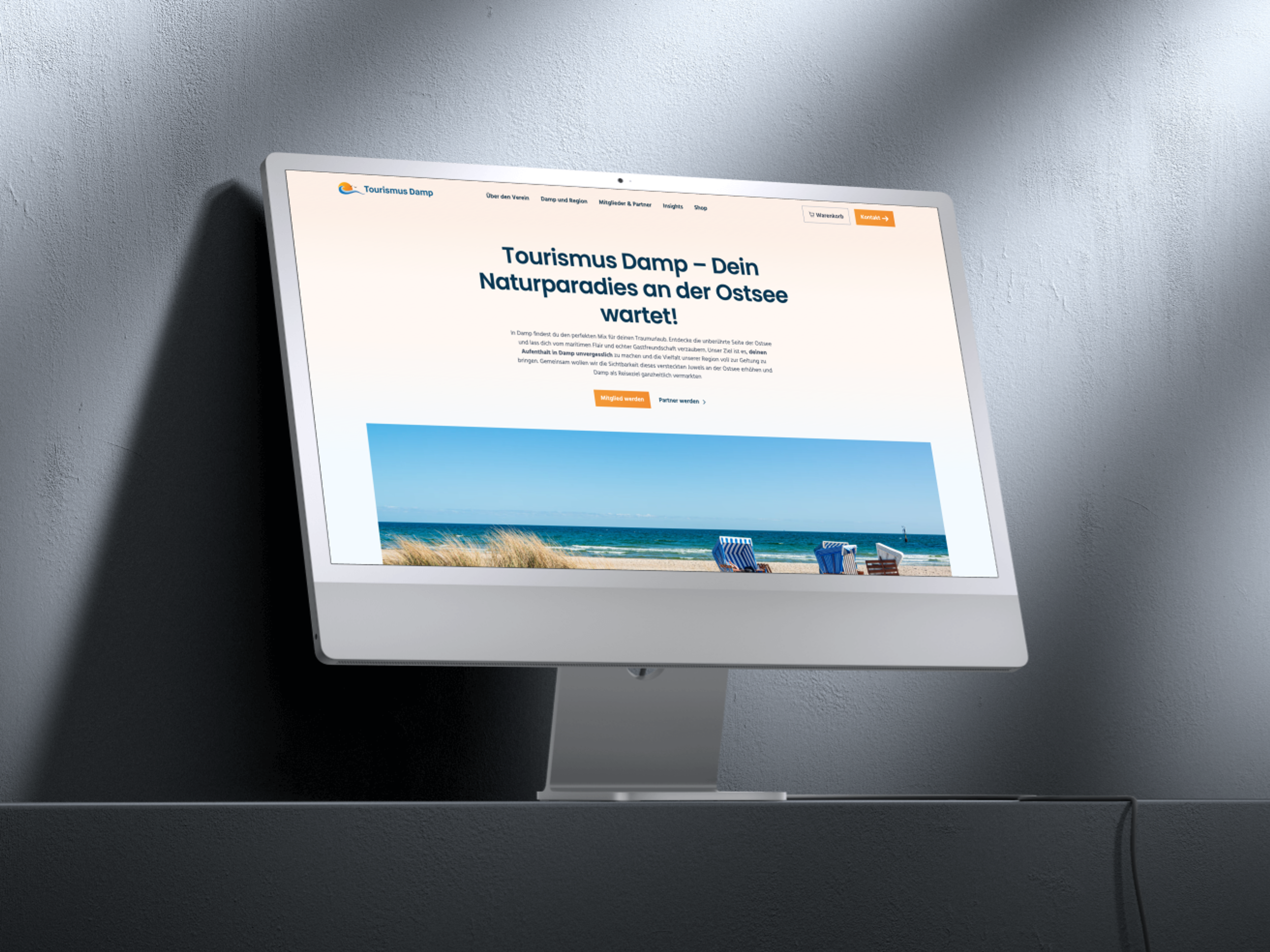 Ein Desktop-Monitor zeigt die Tourismus Damp Website mit einem Strandbild und Informationen über die Ostsee.