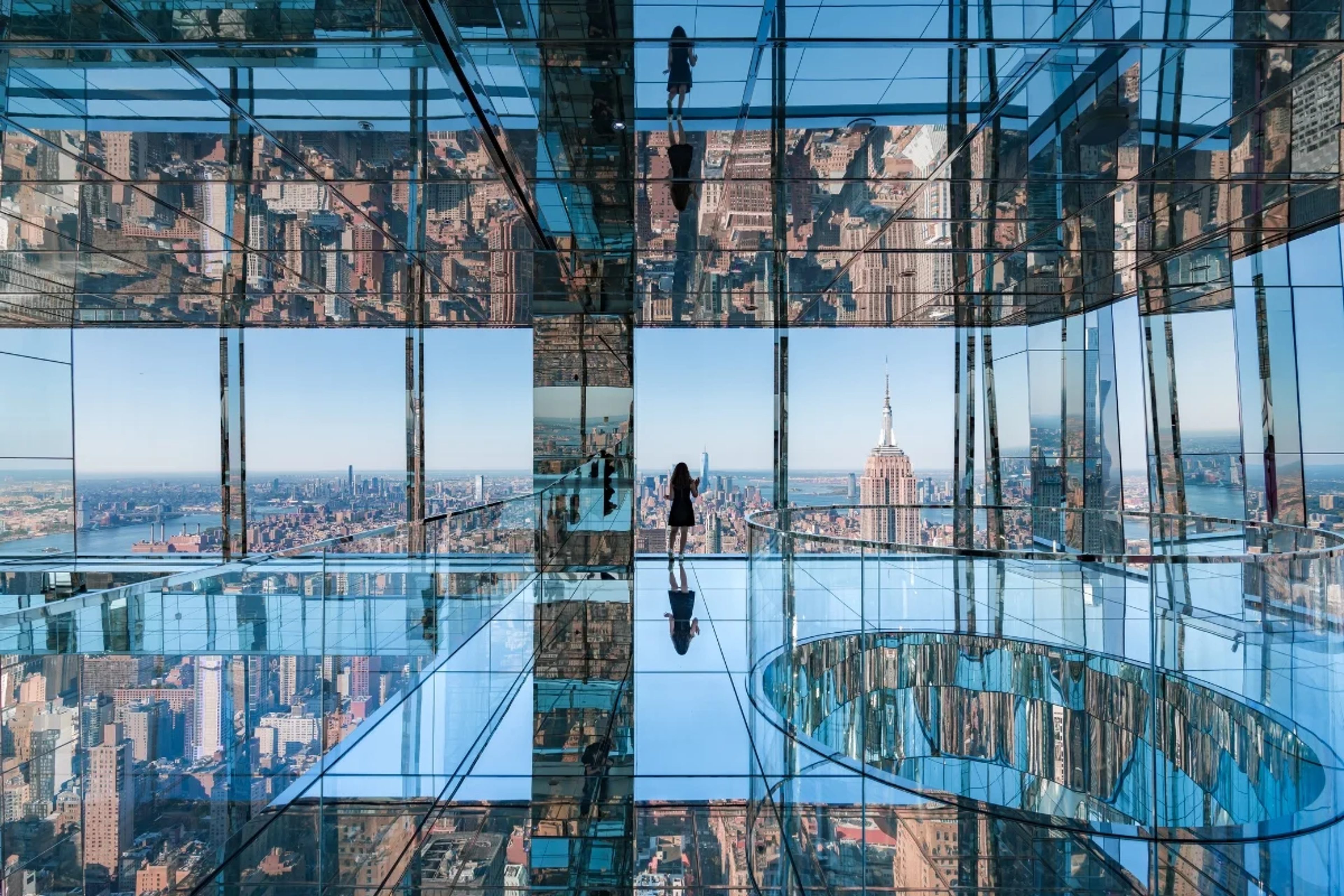 Girl in a black dress standing in empty mirrored room