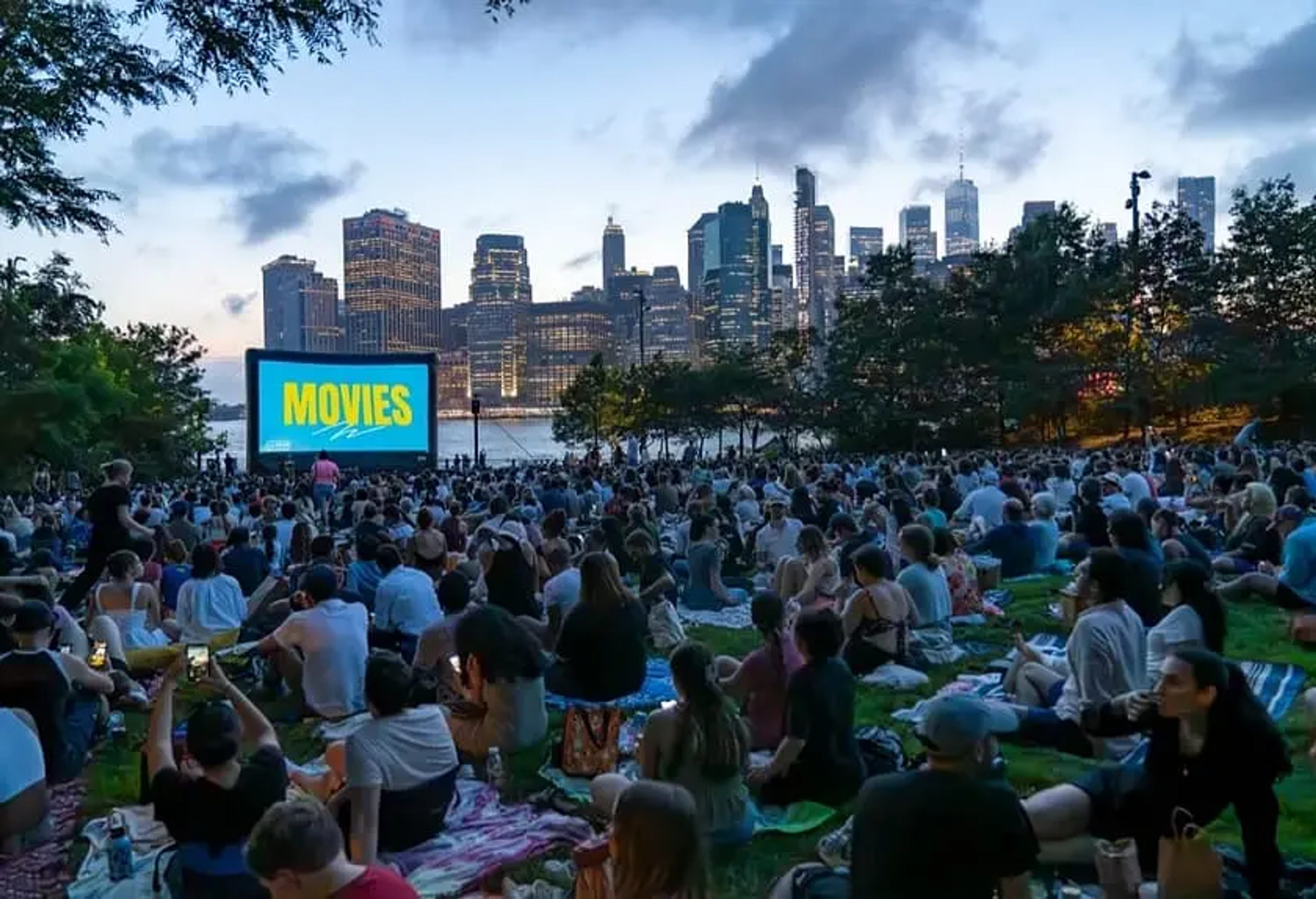 People sitting in Brooklyn Bridge Park watching a big screen