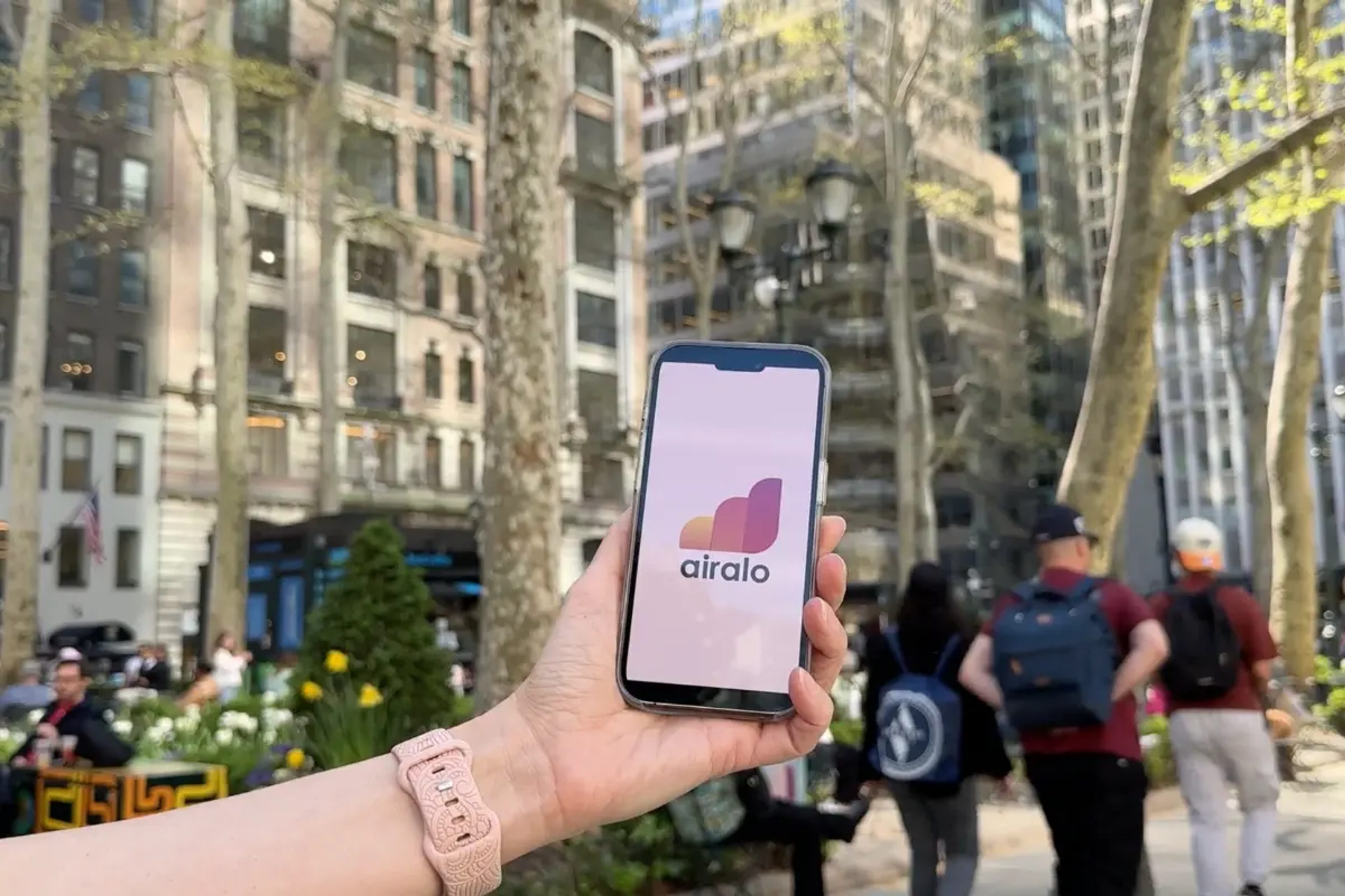 Hand hält ein Handy mit Airalo Logo