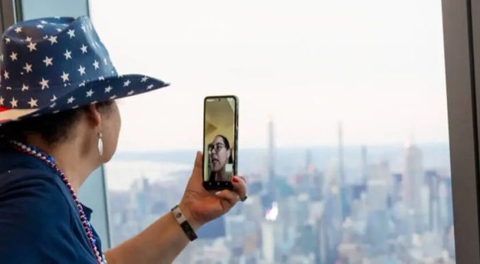 Person with hat in USA colors taking a photo of New York