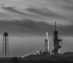 Commercial aerospace rocket on launch pad at dusk, ready for space mission
