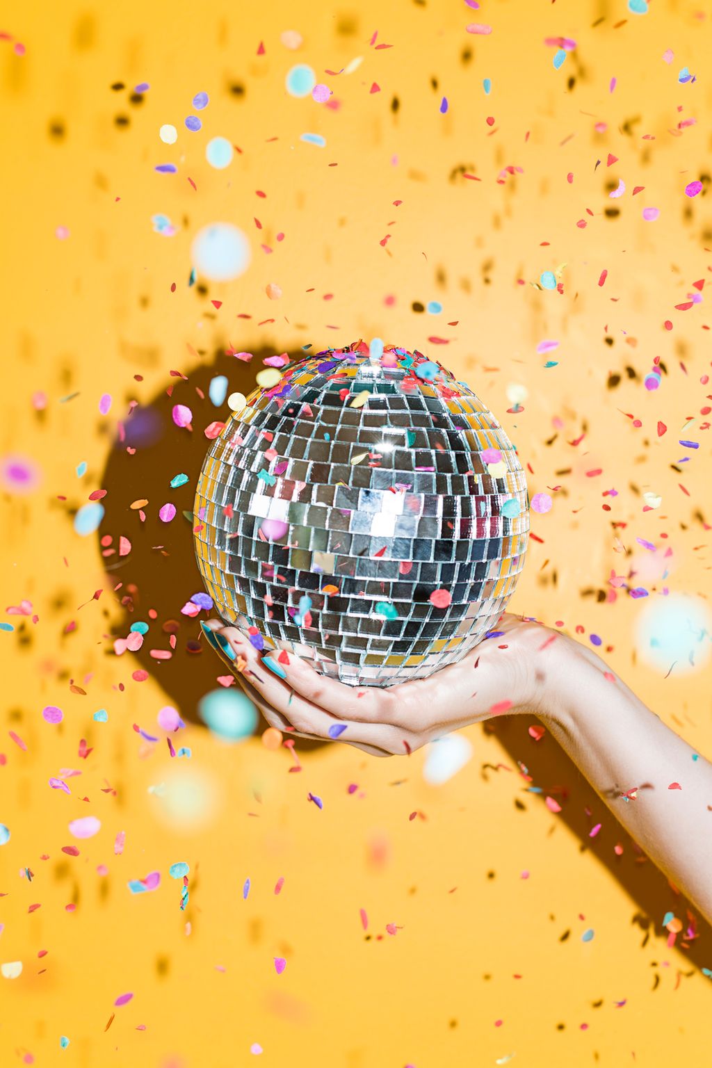 Hand holding disco ball with confetti