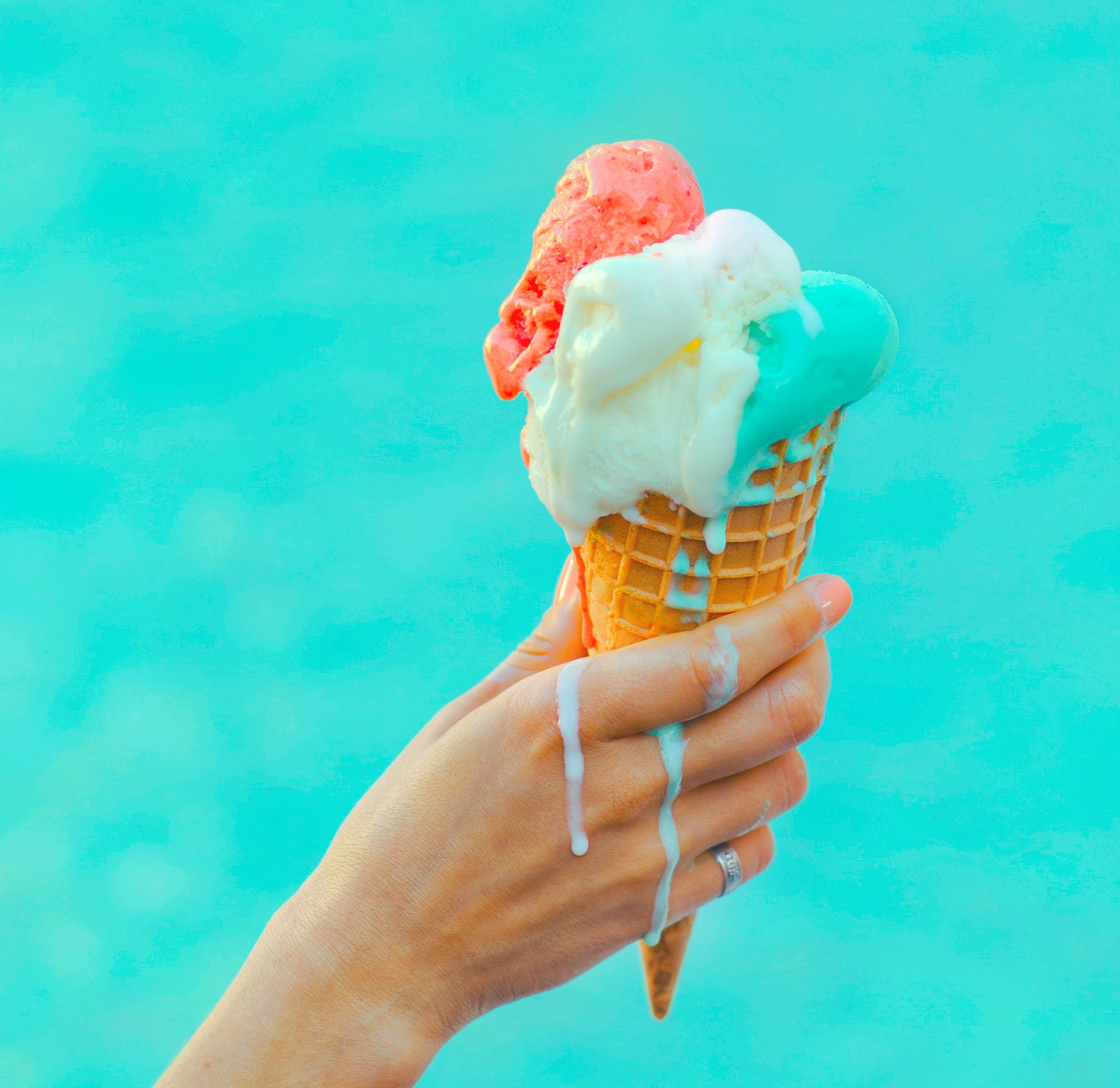 Hand holding melting ice cream cone