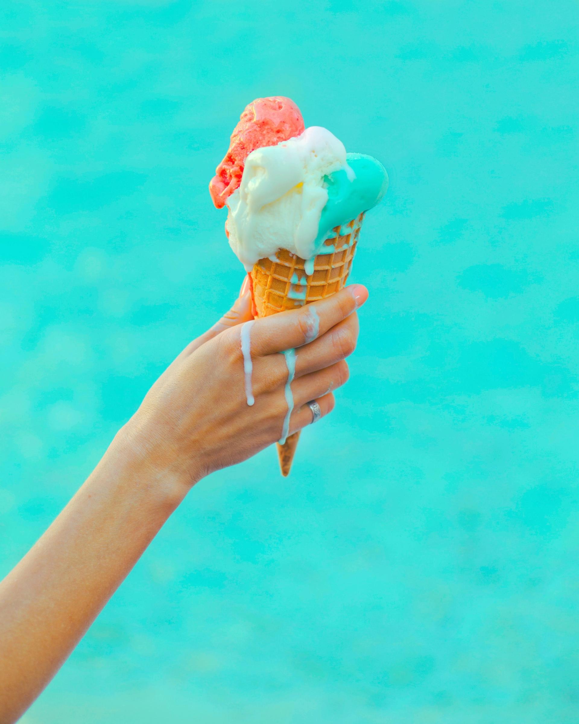 Hand holding melting ice cream cone