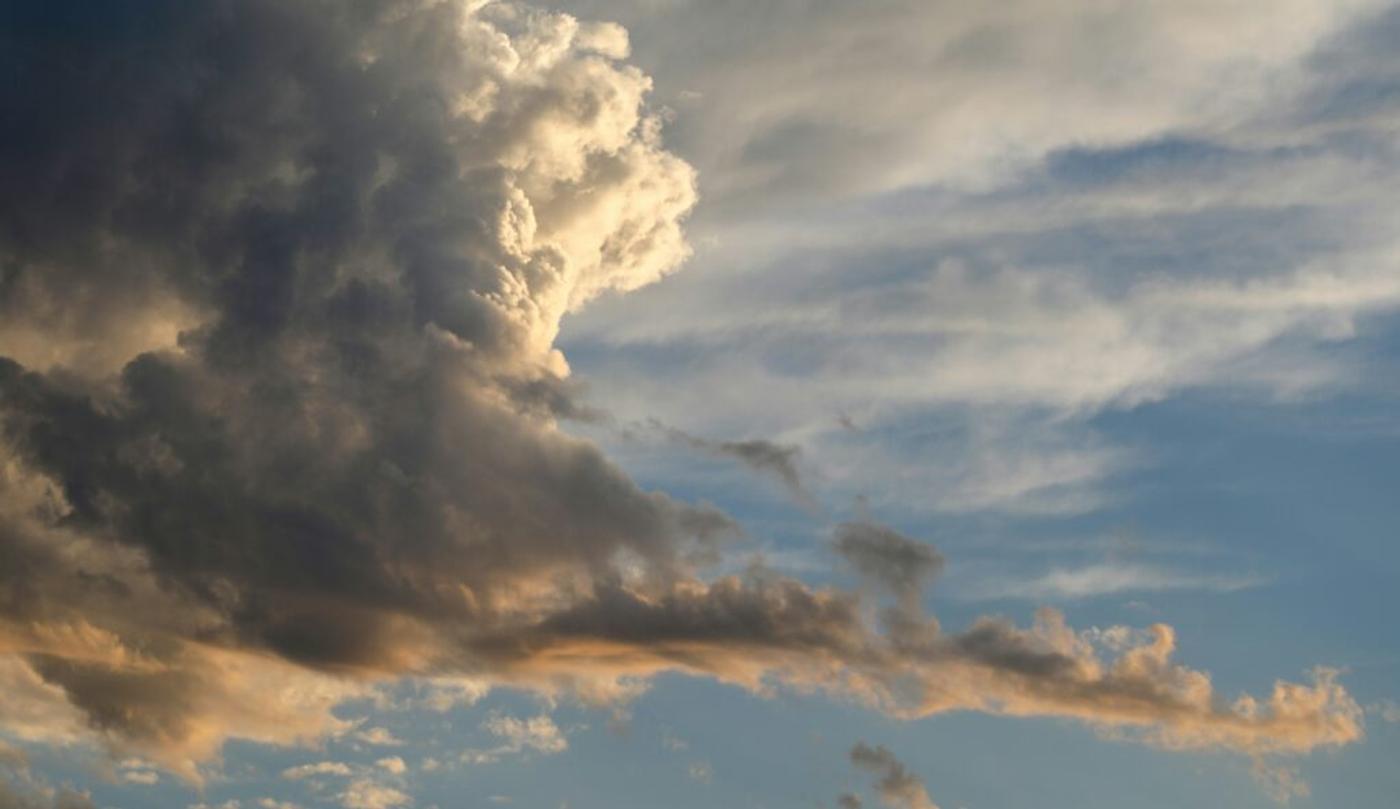 Towering cumulus and wisps of cirrus lit gold at dusk