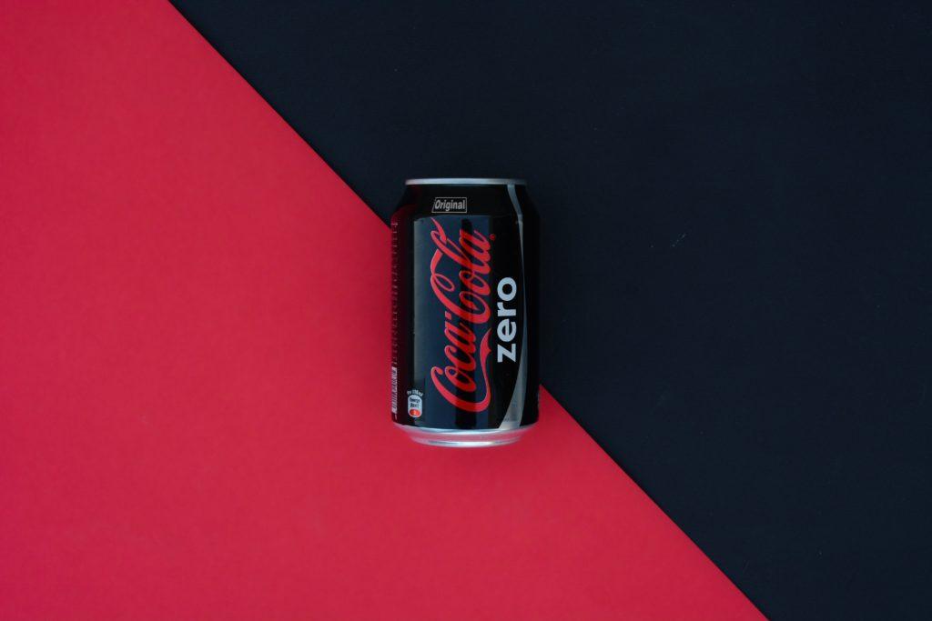 A black can of Coca-Cola Zero on a red and black background.