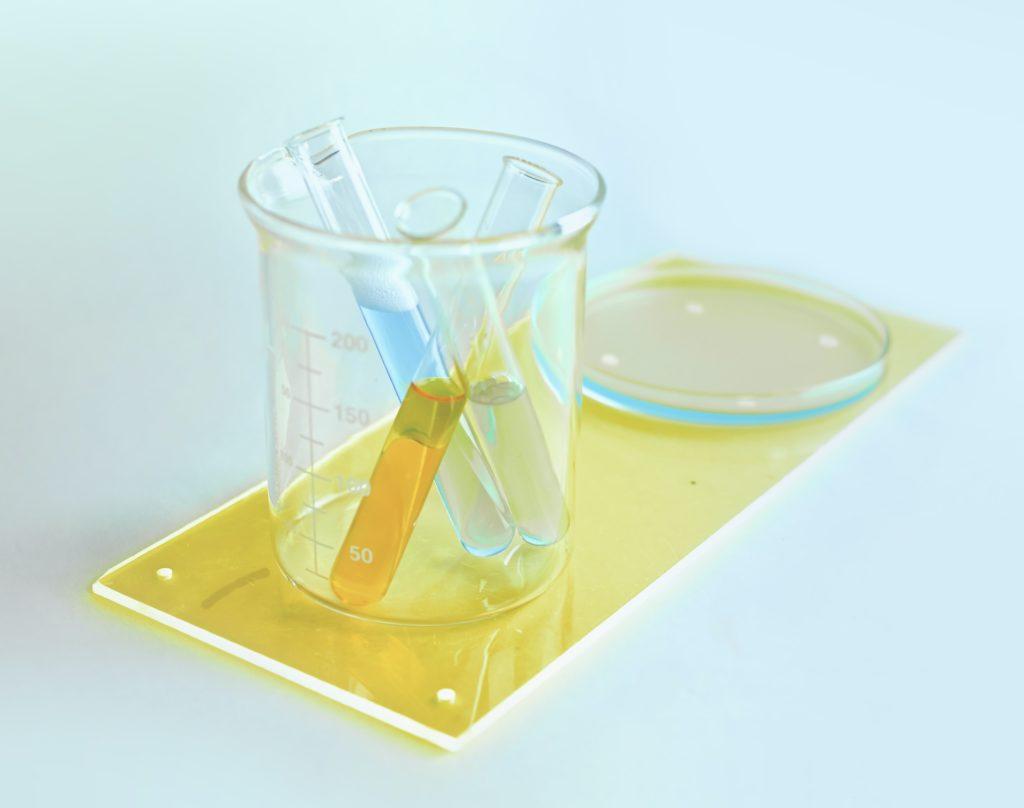 Test tubes in a beaker on a yellow lab tray, washed in pale blue light