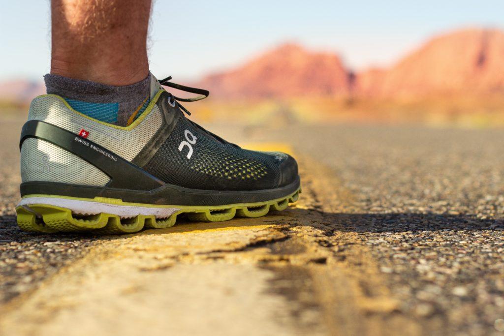 Close-up of an On running shoe with hollow CloudTec pods along its sole, on a desert road.