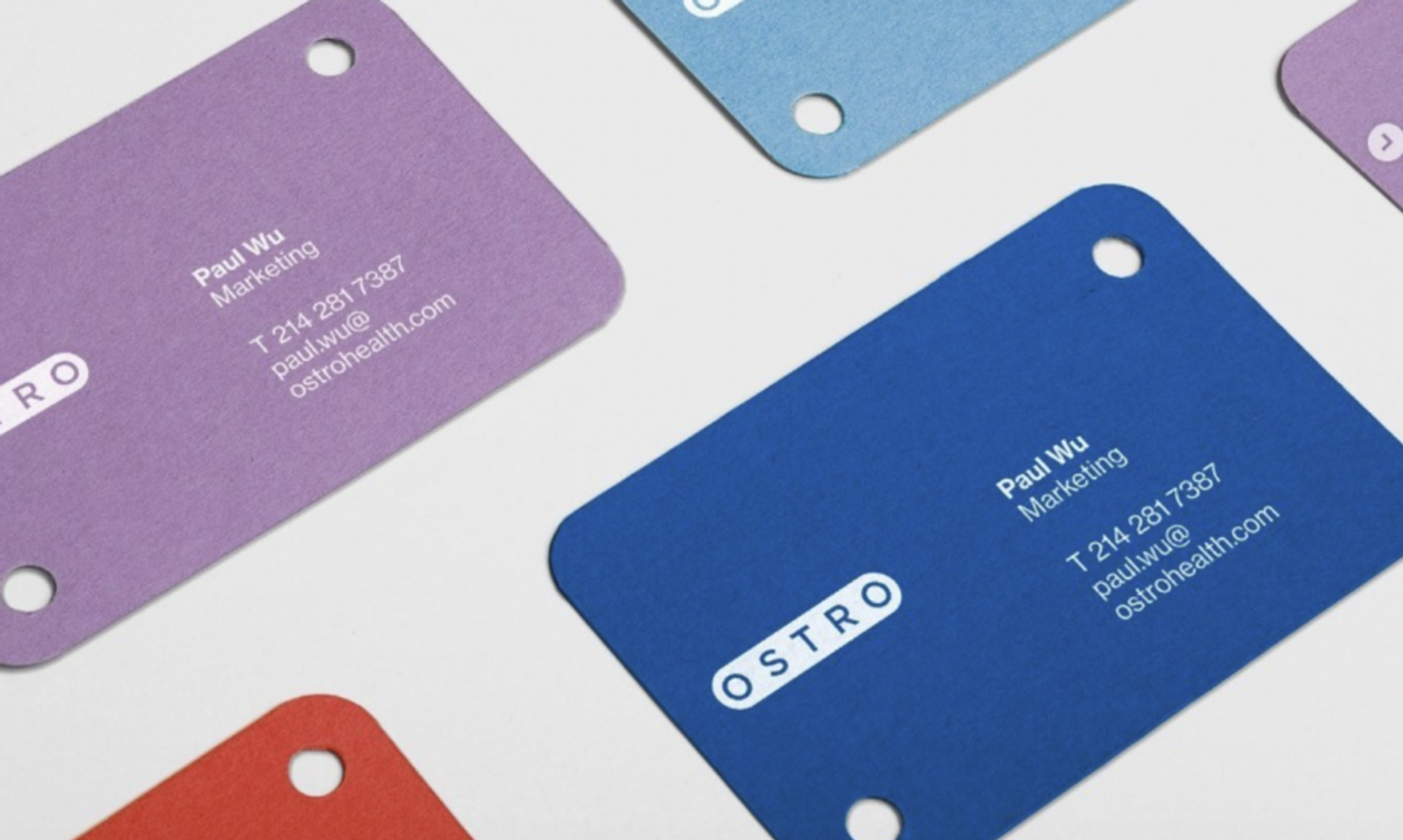 Ostro business cards in purple, blue and red, each punched with a hole
